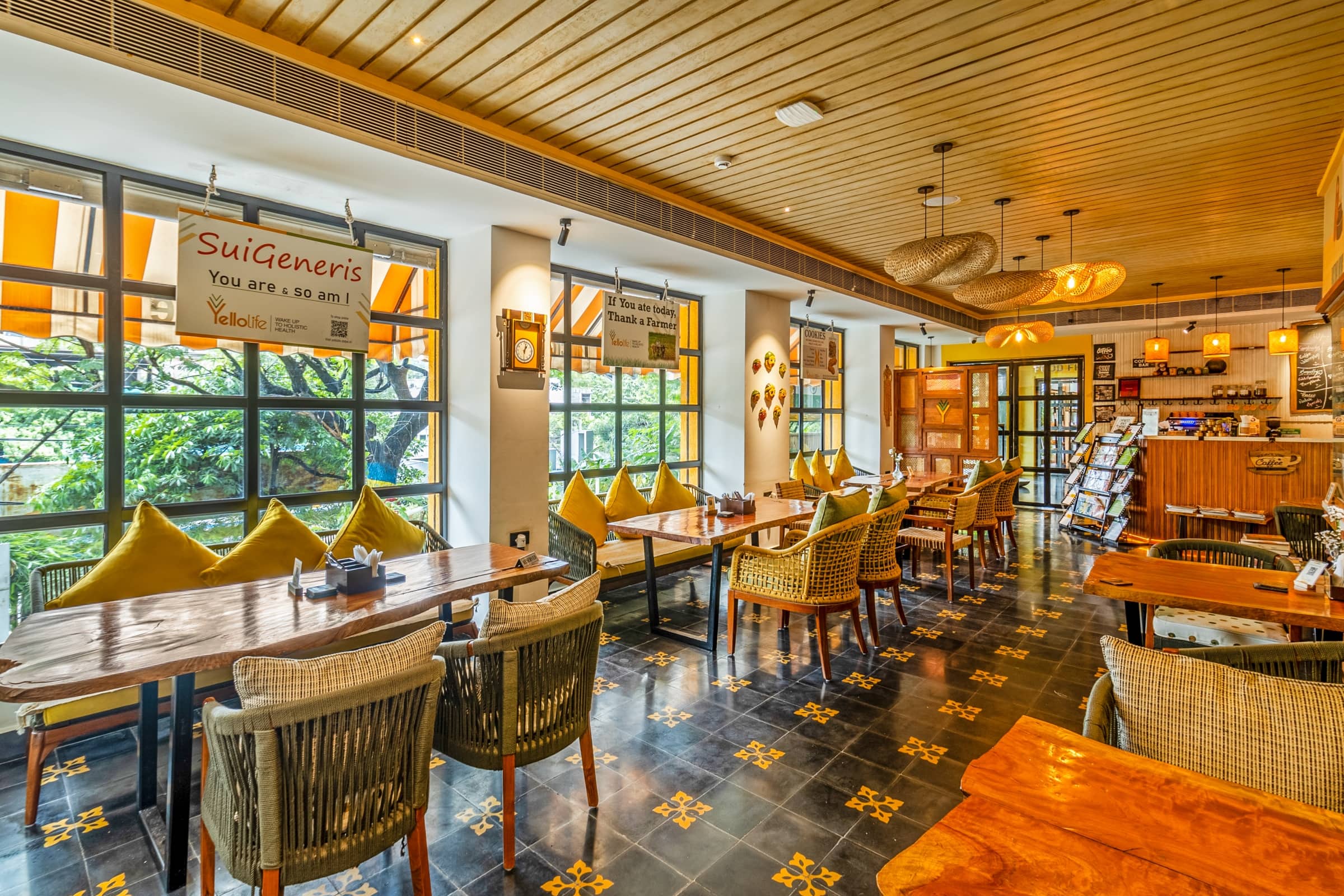 Main dining hall with yellow cushions and rattan chairs at Yellolife Cafe